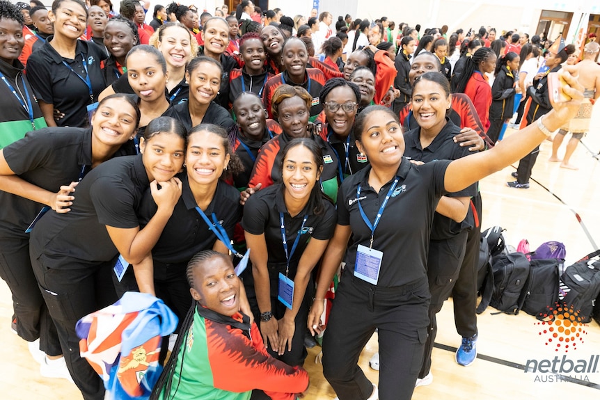 two netball teams  huddle together for a photo after pac aus sports netabll series opening ceremony 