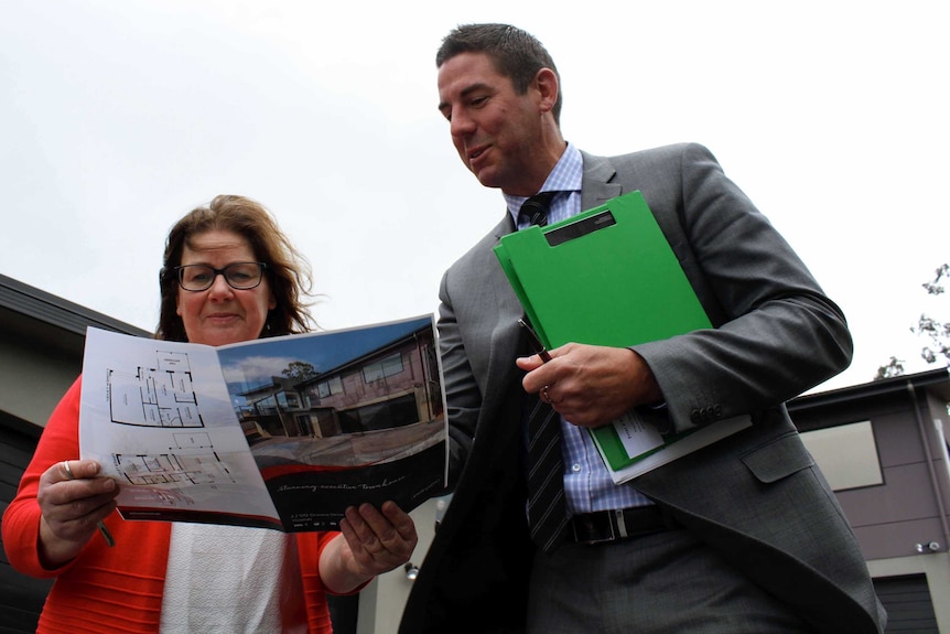 Home buyer looks at pamphlet in Hobart