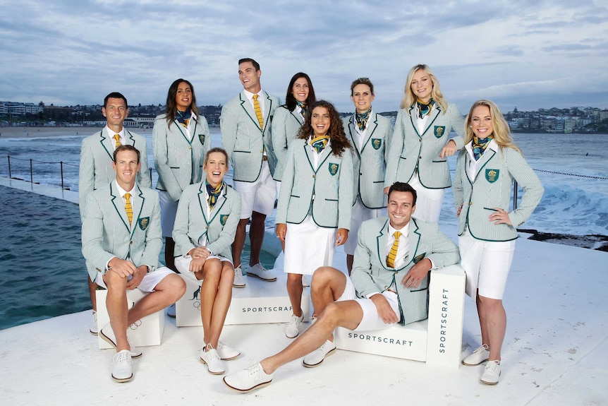 A group of Olympians posing by the Bondi Icebergs in new mint green, pinstriped blazers, white shorts and scarves
