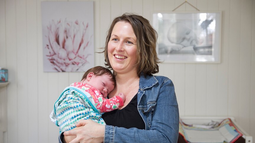 Director Alecia Staines smiling holding her five week old daughter
