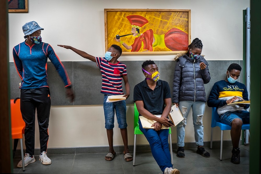 Five people in masks wait in line