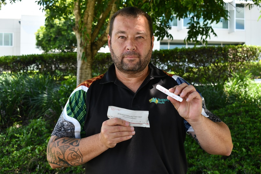 A man holds up a rapid antigen test.