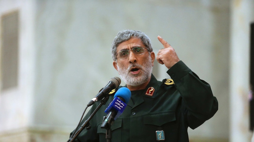 A bearded General Esmail Ghaani in a green uniform gestures as he delivers a speech in 2017.