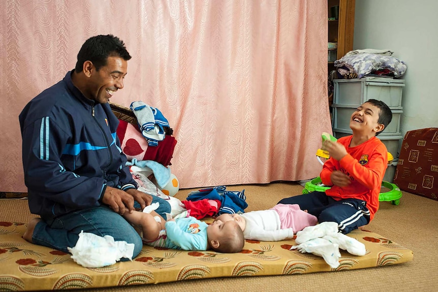 A father and son, asylum seekers from Syria, change the nappies of the family's newly arrived twins