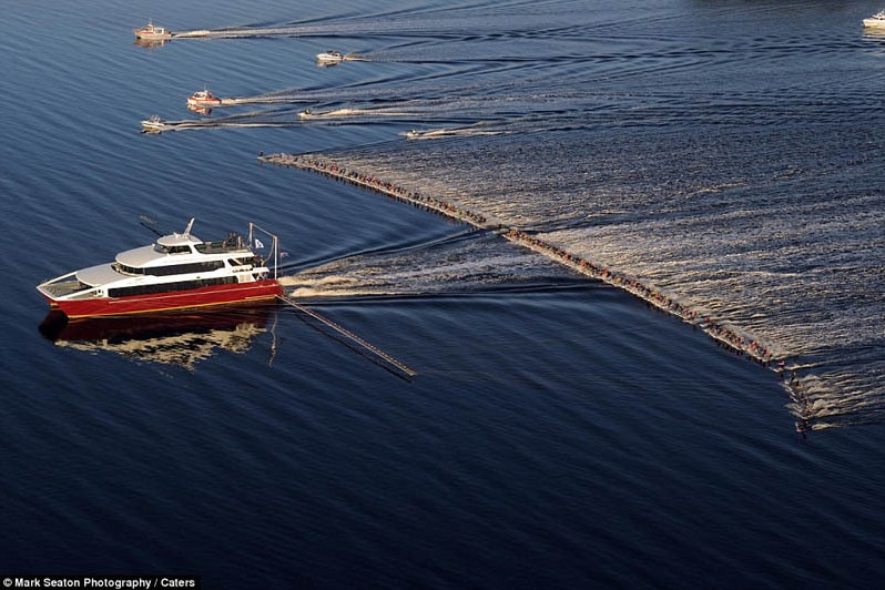 A large group of people water skiing behind a boat.