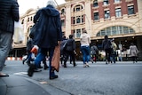 People walk across the street towards Flinders Street Station.