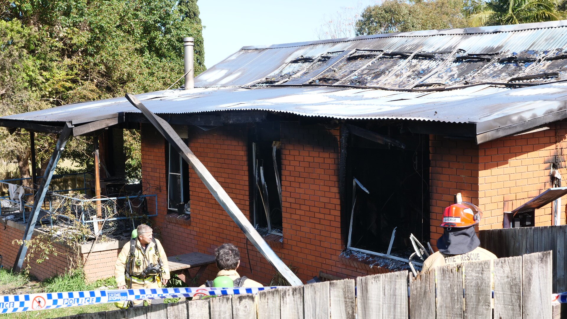 A brick house with tin roof damaged by fire.