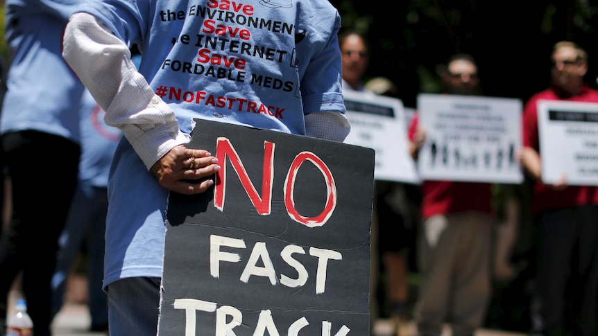 Demonstrator holds sign protesting Trans-Pacific Partnership fast track