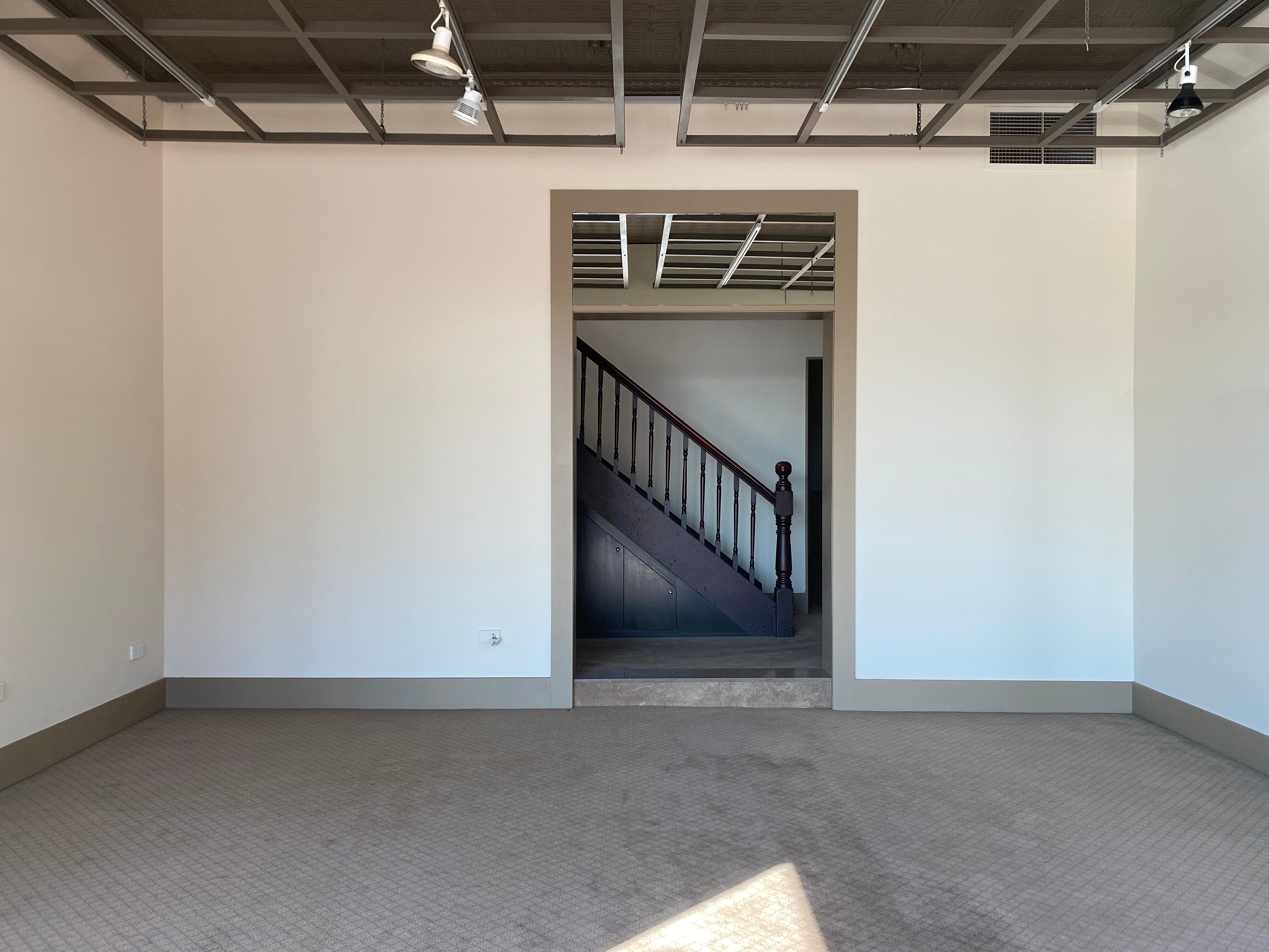 An empty storefront with a view through a door onto a staircase.