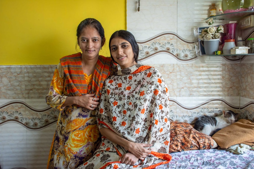 Two women inside a house next to a sleeping cat