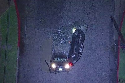 An aerial view of the California sinkhole shows two cars stuck inside.