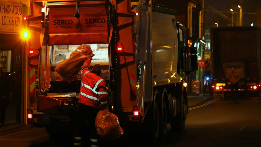 A worker throws rubbish into a garbage truck in England.
