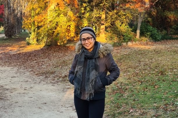 Felia standing in the middle of a road with Autumn trees behind her. 