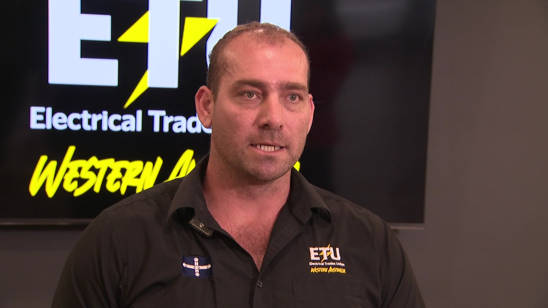 El Secretario de Estado de Electrical Trades Union WA, Adam Woodage, habla con un polo negro de ETU.