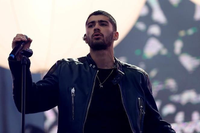 A man wearing a black leather jacket performing on stage