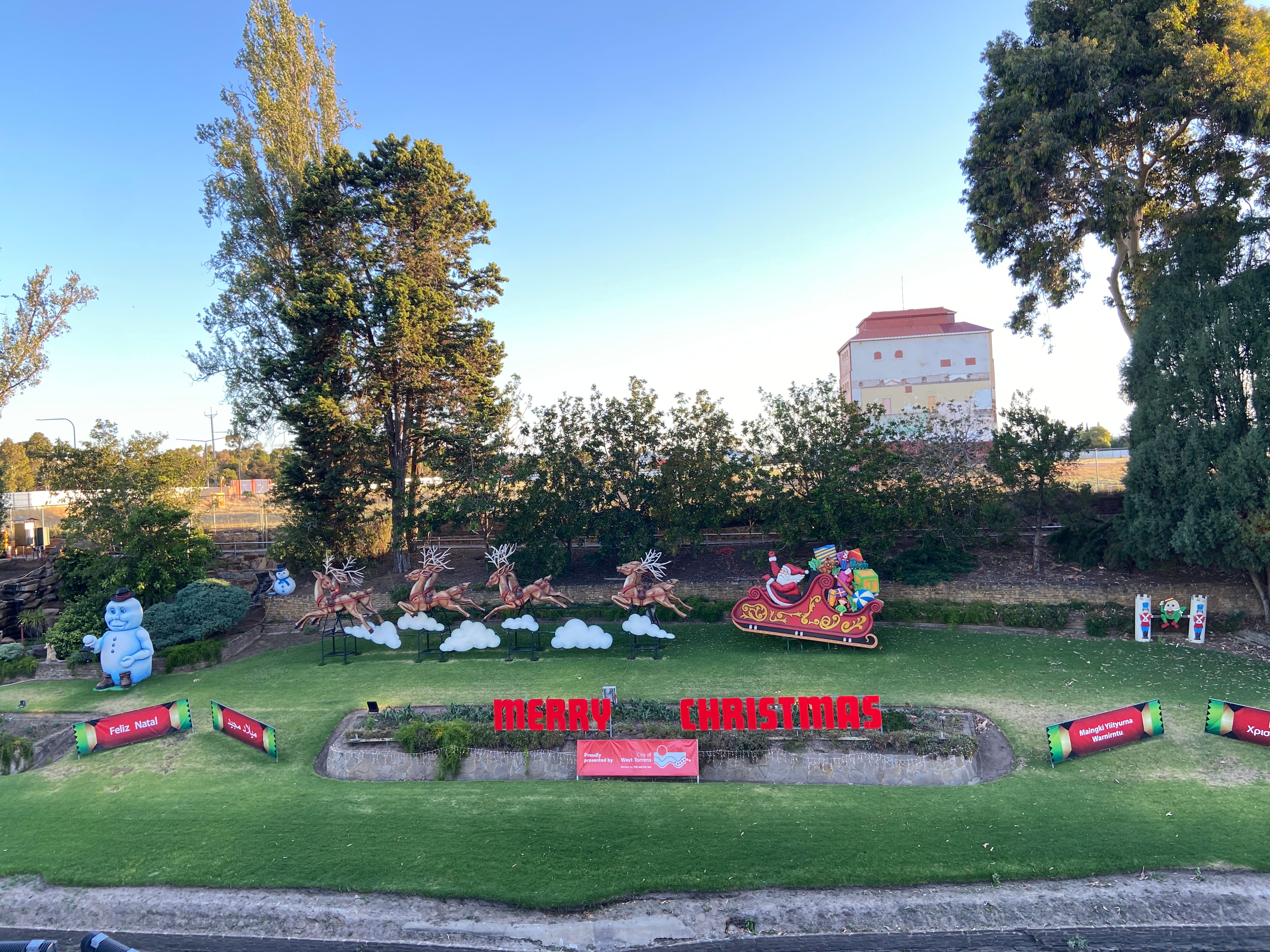 Una serie de instalaciones navideñas, incluido un trineo de Papá Noel con renos, a lo largo de la orilla de un río.