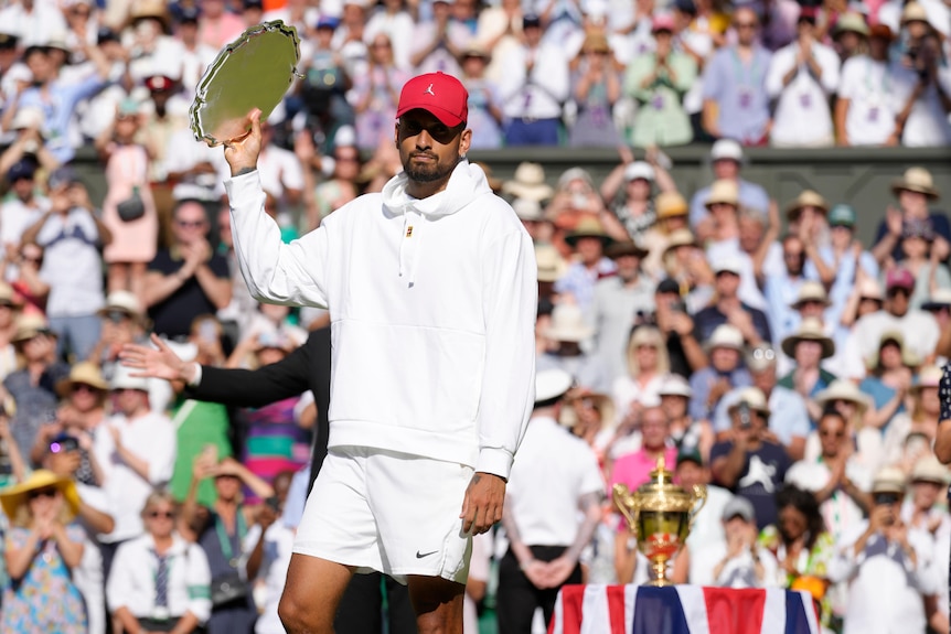 Nick Kyrgios holds aloft the runner-up Wimbledon trophy after losing the final to Novak Djokovic.