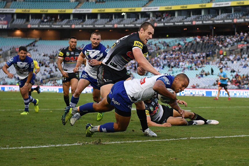 Moses Mbye of the Bulldogs barges through a tackle to score against Penrith at the Olympic stadium.