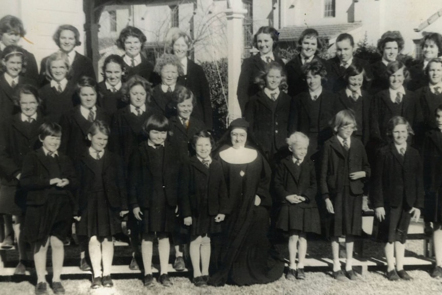 A black and white group photo of about 20 children and a nun