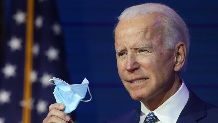 US vice-president elect Joe Biden holds a surgical mask.