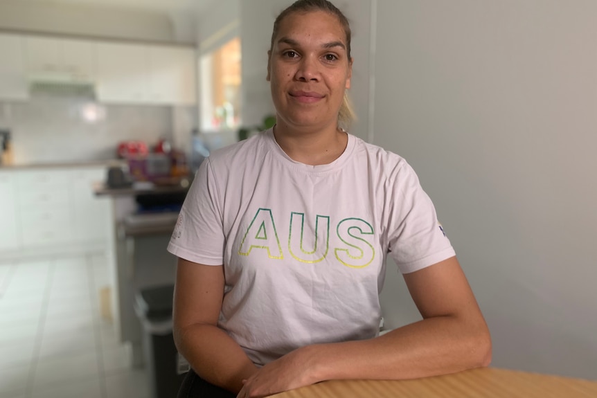 Indigenous woman wearing a grey shirt sitting at a table.