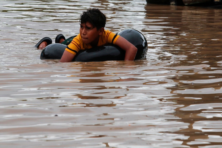 A child floats on an inner tube in a flooded street in the aftermath of Hurricane Eta, in Planeta, Honduras.