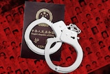 A graphic with a pair of handcuffs sitting on a Chinese passport.