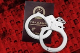 A graphic depicts a list of wanted suspects with a Chinese passport and handcuffs
