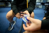 Fidget spinner in hands of children sitting in classroom.