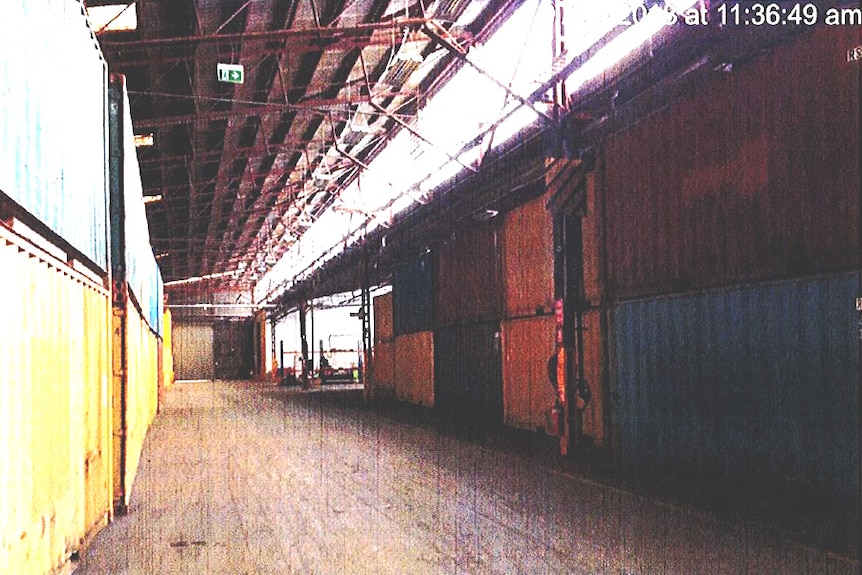 Coloured shipping containers sit inside a warehouse.
