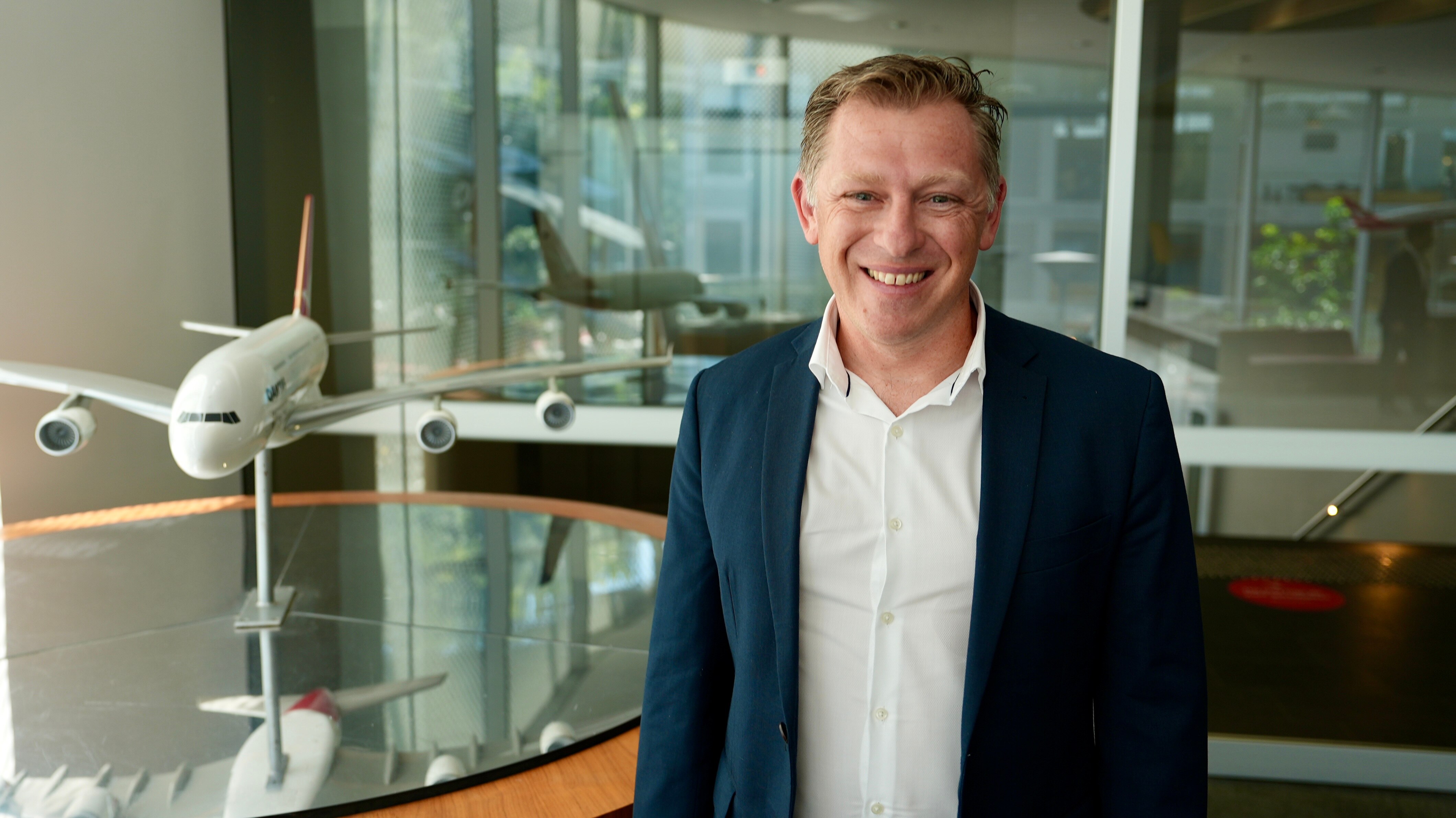 Man wearing a suit, with a model plane next to him.