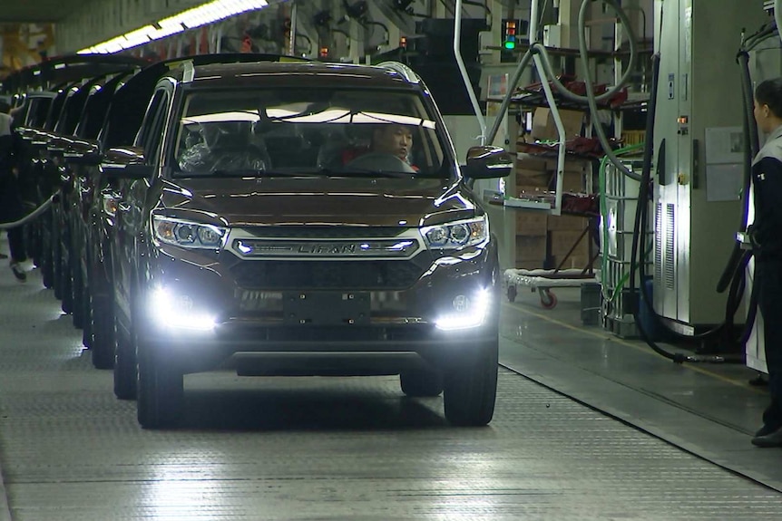 A worker sits in an SUV on a production line.