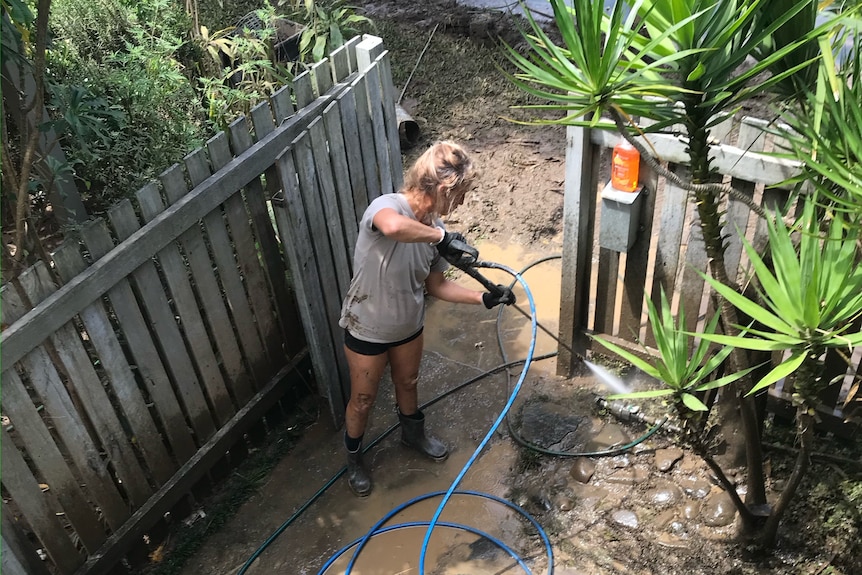 Woman cleaning out muddy water from her front yard using a gurney.