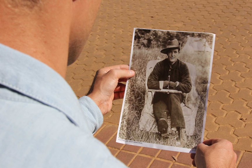 A man holds a photo of an unknown World War I soldier, who is missing his hands, from the Australian War Memorial collection.