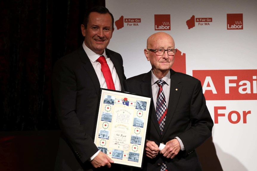 WA Premier Mark McGowan and former deputy premier Mal Bryce on stage posing for a photo holding a framed life membership.