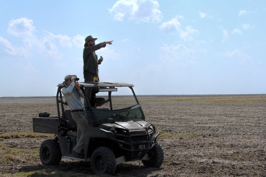Ornithologist Chris Sanderson and senior ranger Khan Spokes use binoculars to look across a dry flood plain at Kakadu.