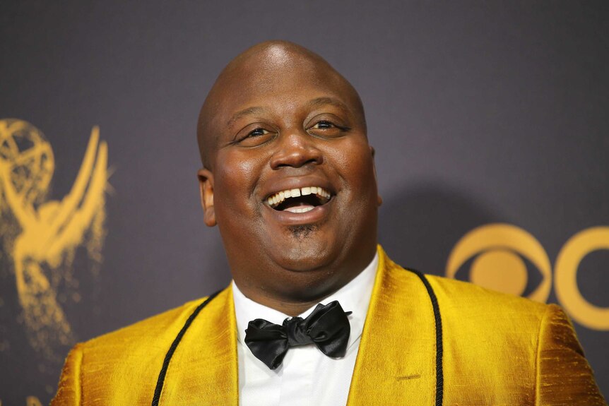 Tituss Burgess wears a bright yellow gold suit and looks thrilled to be on the red carpet