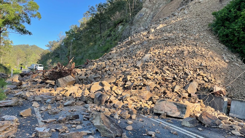 Rocks and rubble from a landslip block a rural road.