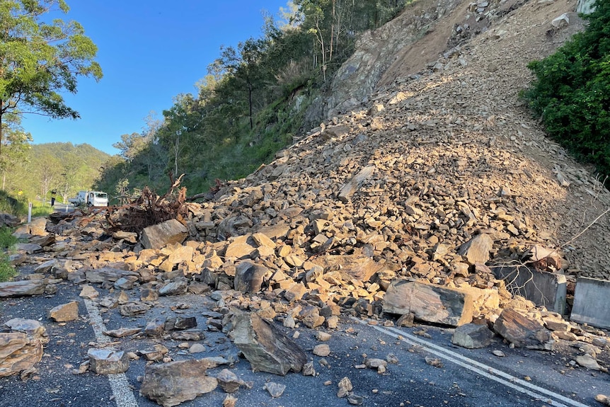 Rocks and rubble from a landslip block a rural road.