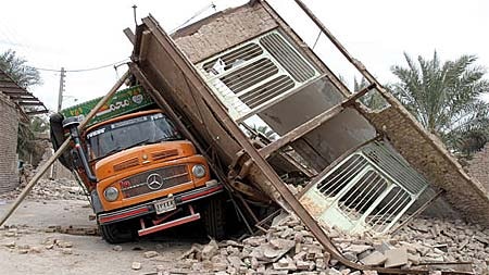 A house leans against a truck after an earthquake in Bam in south-eastern Iran.