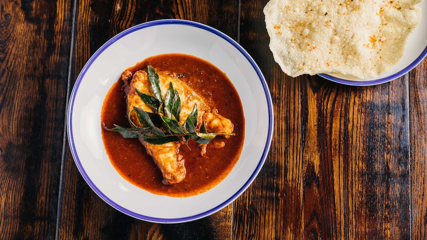 Fish Nadan curry with accompanying parota on seperate blue-rimmed white plates.