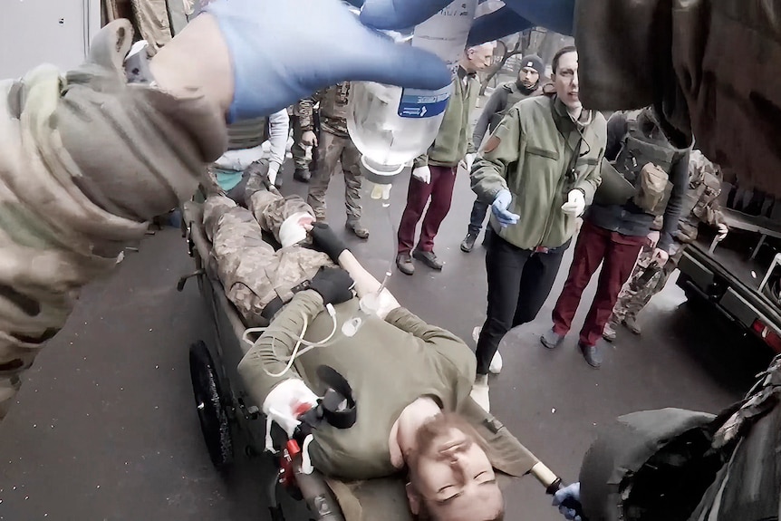 Yuliia Paievska, known as Taira, watches as a serviceman is brought on a stretcher to Mariupol.