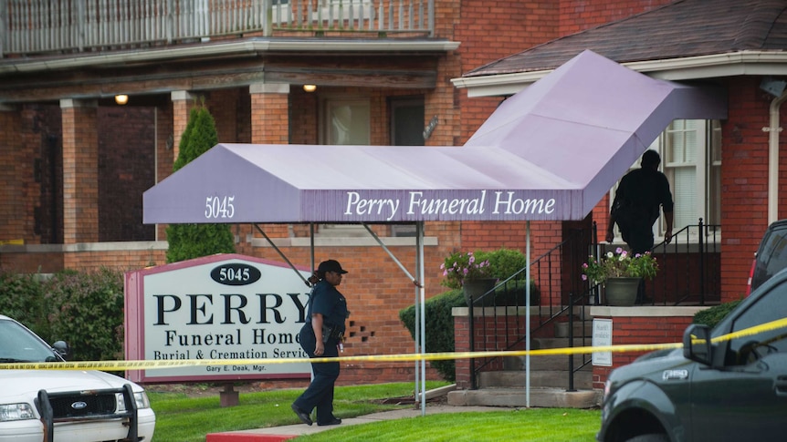 A police officer stands outside the Perry Funeral Home which has been taped off.