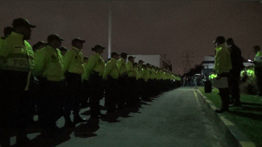 A line of dozens of police officers in bright yellow jackets.