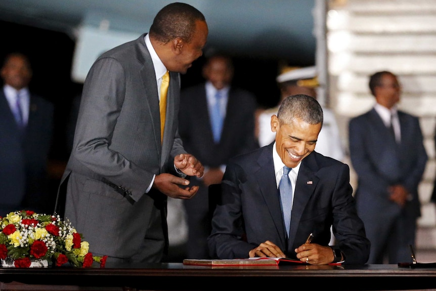 Kenya's president Uhuru Kenyatta looks on as US president Barack Obama signs a guest book as he arrives in Nairobi.
