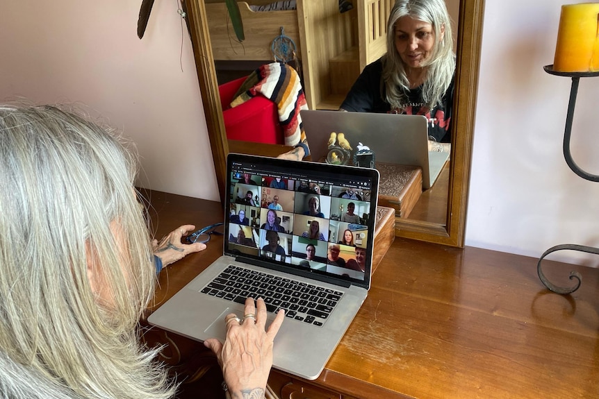 Women sit in front of laptops, on the screen of which people can be seen via video. 