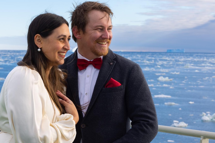 Briege Whitehead and her fiance Benn Ellard on board the RSV Nuyina, smiling as they look out over the ice.