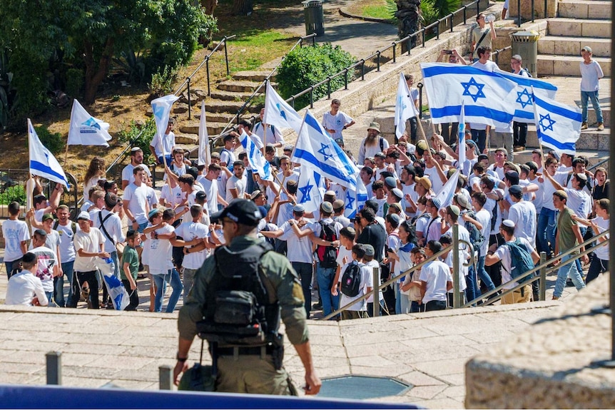 A large crowd of people, with many holding Israeli flags