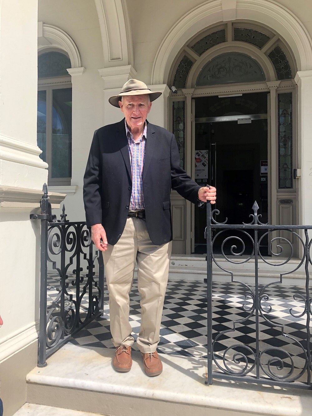 Tom Wyatt stands at the top of stairs at ABC Capricornia, a sandstone building