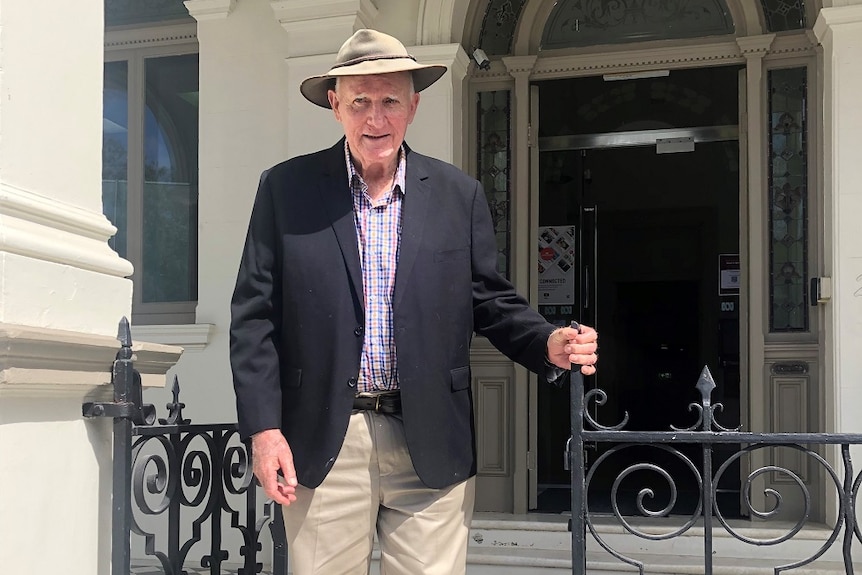 Tom Wyatt stands at the top of stairs at ABC Capricornia, a sandstone building